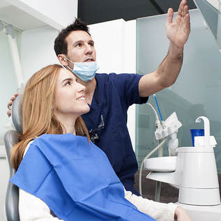 Picture of a female patient in the dental chair looking at xrays with her dentist.